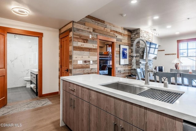 kitchen with light hardwood / wood-style flooring, wooden walls, and sink