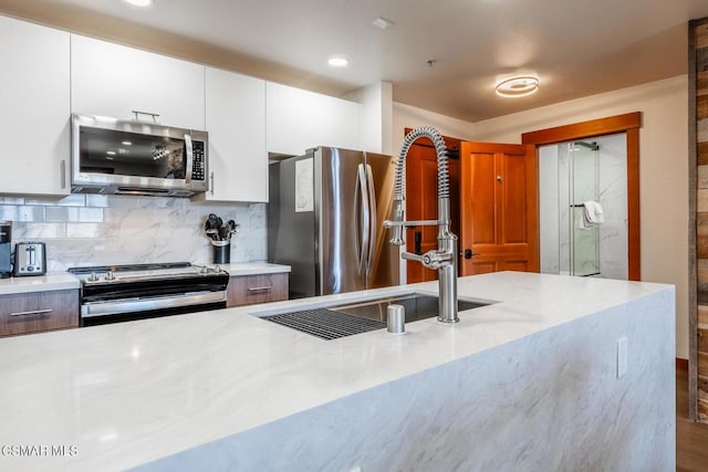 kitchen with appliances with stainless steel finishes, tasteful backsplash, white cabinetry, and sink