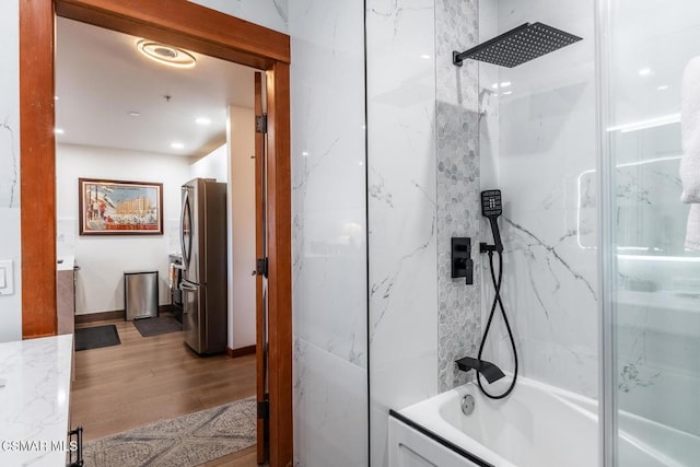 bathroom featuring shower / bath combination with glass door, wood-type flooring, and tile walls