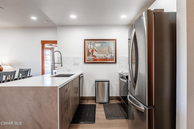 kitchen with kitchen peninsula, decorative backsplash, sink, and appliances with stainless steel finishes