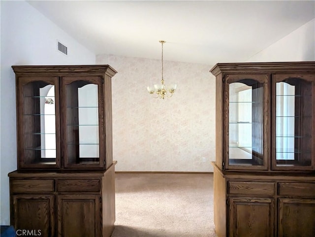 carpeted dining space with vaulted ceiling and an inviting chandelier