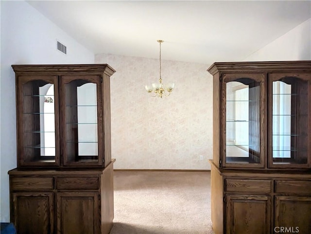 interior space with vaulted ceiling, a notable chandelier, baseboards, and visible vents