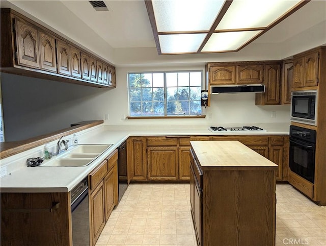 kitchen featuring black appliances, butcher block counters, sink, and a center island