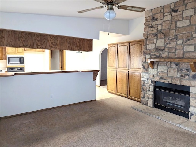 unfurnished living room with light carpet, ceiling fan, and a fireplace