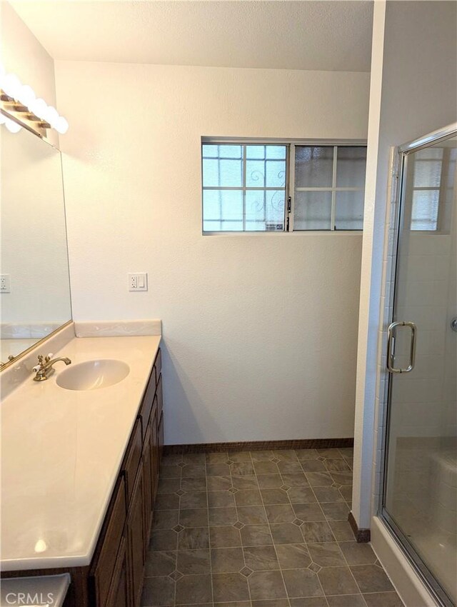 bathroom featuring a shower with shower door, vanity, and tile patterned flooring