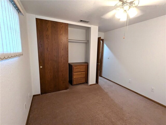 unfurnished bedroom with ceiling fan, a closet, and light carpet