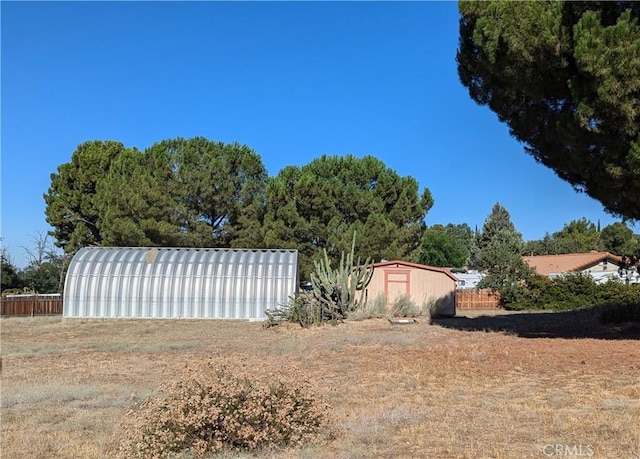 view of yard with a storage shed, an outdoor structure, and fence