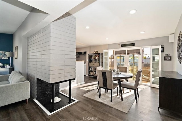 dining area featuring a brick fireplace and dark hardwood / wood-style floors