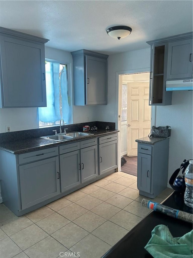 kitchen with light tile patterned floors, gray cabinetry, and sink