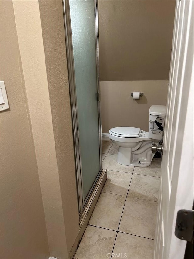 bathroom featuring tile patterned floors, toilet, a shower with door, and lofted ceiling