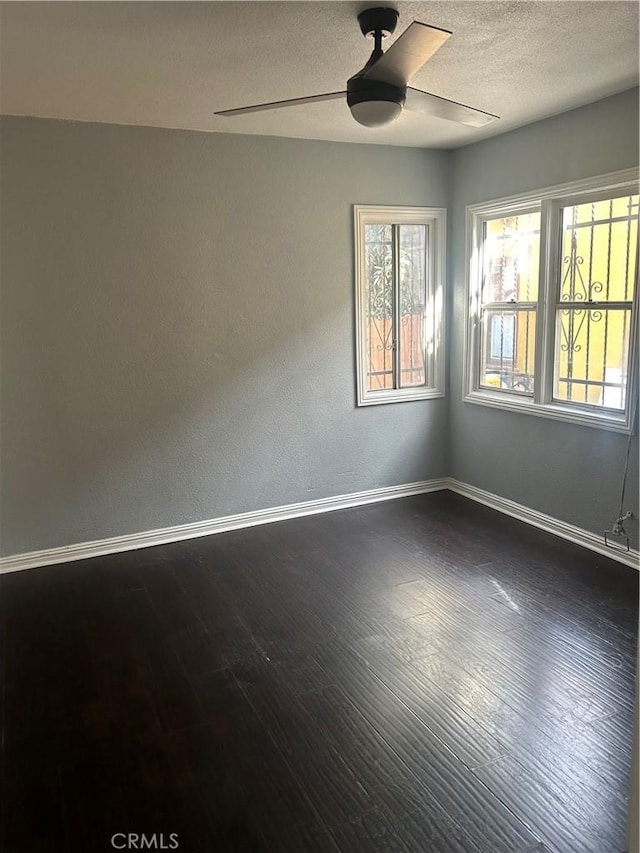 spare room with ceiling fan, a textured ceiling, and dark hardwood / wood-style flooring