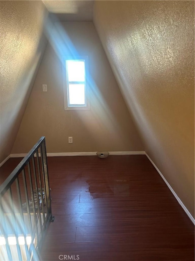 additional living space with vaulted ceiling and dark hardwood / wood-style floors