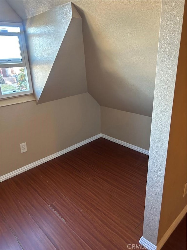 bonus room with vaulted ceiling, dark hardwood / wood-style flooring, and a textured ceiling