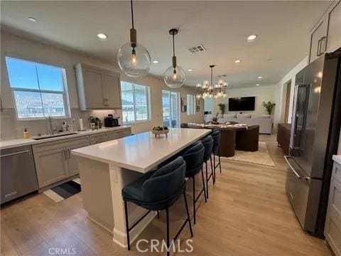 kitchen with a breakfast bar, appliances with stainless steel finishes, gray cabinetry, and a center island