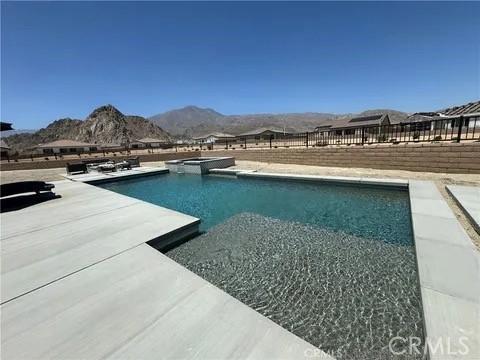 view of swimming pool with a patio area, a mountain view, and an in ground hot tub