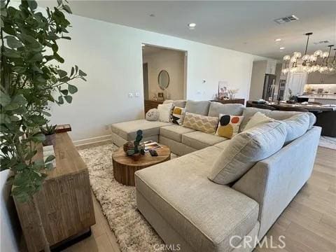 living room featuring light wood-type flooring and an inviting chandelier