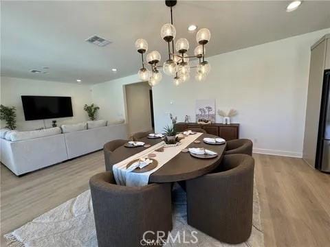 dining room with light hardwood / wood-style floors and a notable chandelier