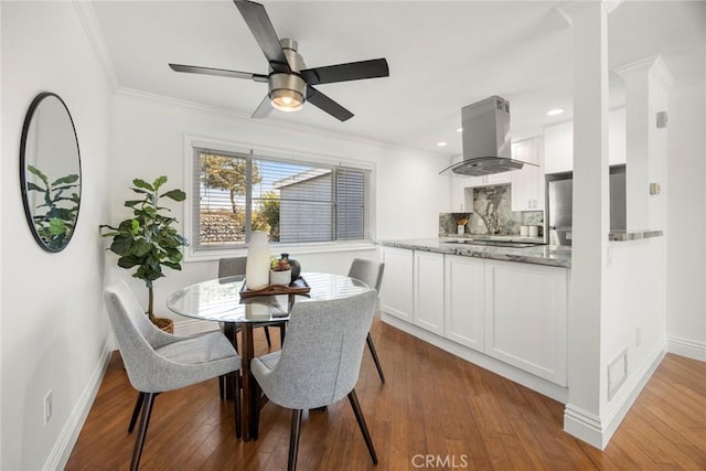 dining area featuring hardwood / wood-style flooring, crown molding, and ceiling fan