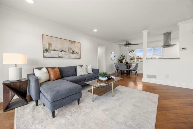 living room featuring hardwood / wood-style flooring, ceiling fan, and crown molding