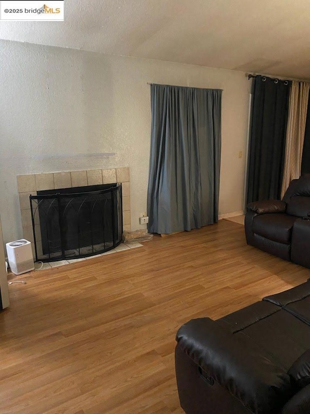 living room featuring a tile fireplace and hardwood / wood-style floors