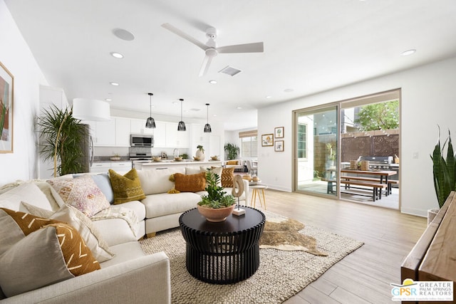 living room featuring ceiling fan, light hardwood / wood-style floors, and sink