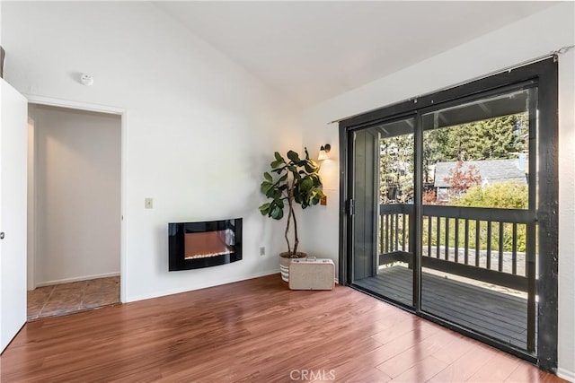 doorway with hardwood / wood-style floors and vaulted ceiling