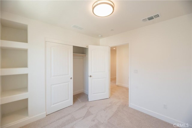 unfurnished bedroom with light carpet and a closet