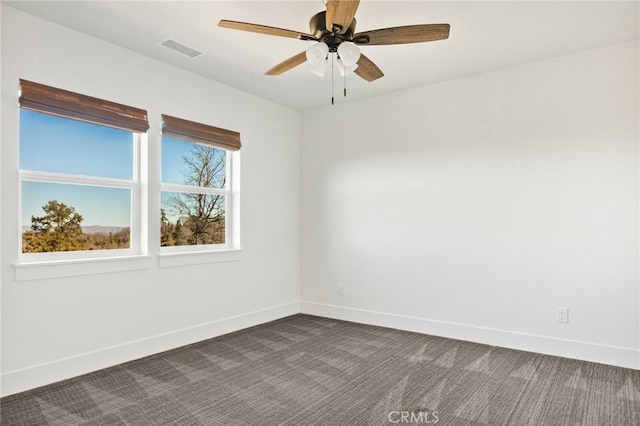 empty room with ceiling fan and dark colored carpet