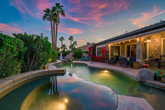 pool at dusk featuring a patio