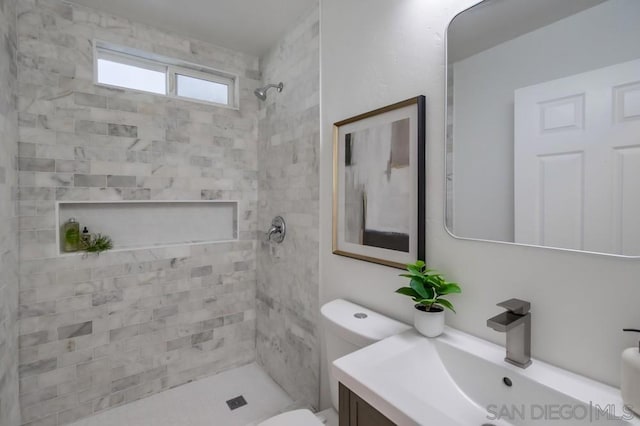 bathroom featuring vanity, toilet, and a tile shower