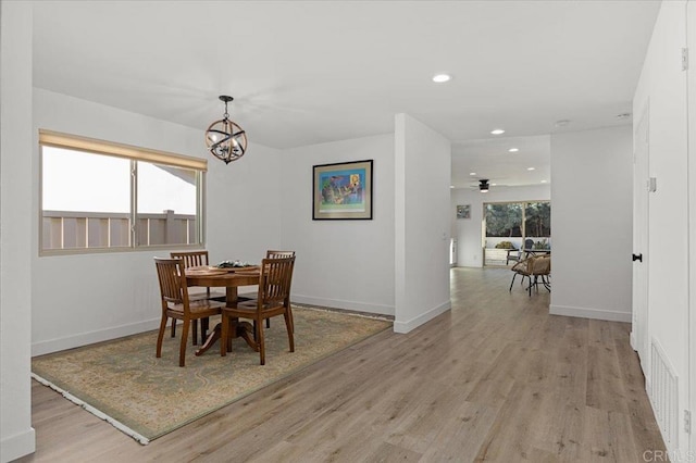 dining area featuring ceiling fan with notable chandelier and light wood-type flooring