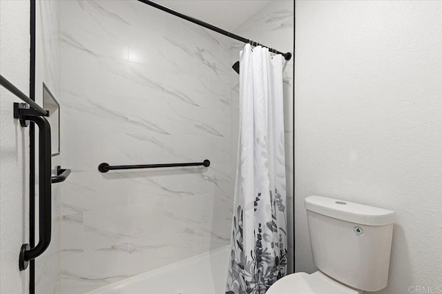 bathroom featuring toilet and curtained shower