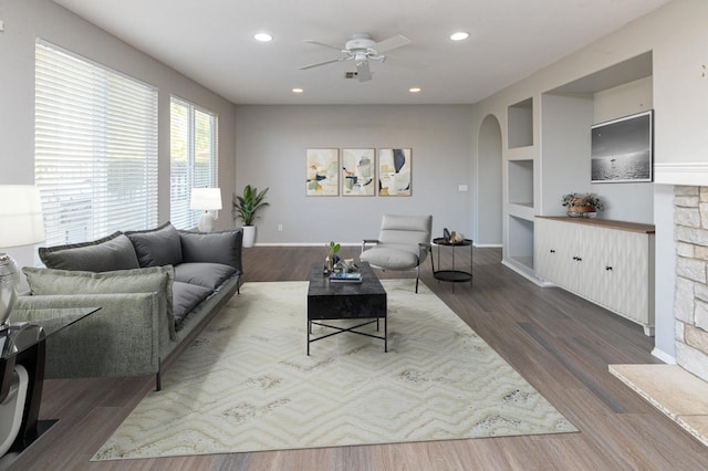 living room with hardwood / wood-style flooring, built in shelves, and ceiling fan