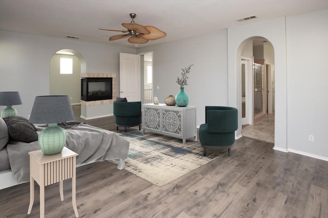 living room featuring ceiling fan, wood-type flooring, and a fireplace