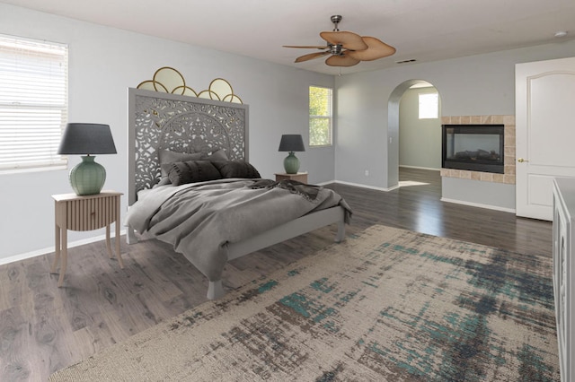 bedroom featuring ceiling fan, dark hardwood / wood-style floors, and a tile fireplace