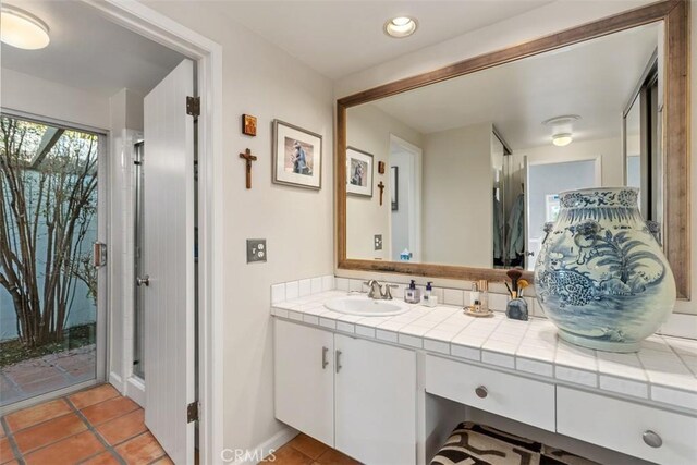 bathroom with a shower with shower door, tile patterned floors, and vanity