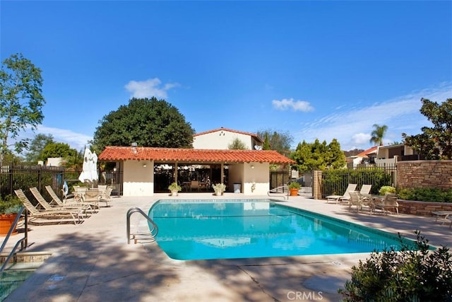 community pool with a patio area and fence