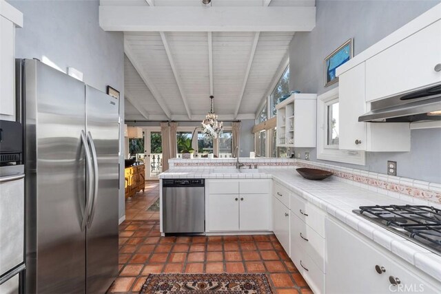 kitchen with white cabinets, stainless steel appliances, sink, tile countertops, and beam ceiling