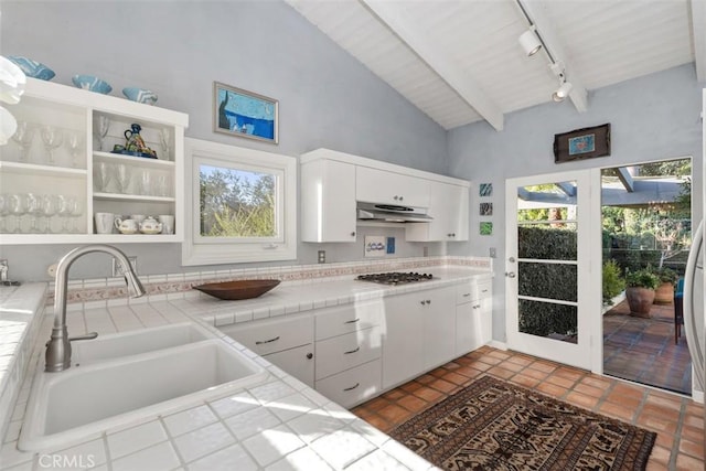 kitchen with under cabinet range hood, white cabinetry, tile counters, and open shelves