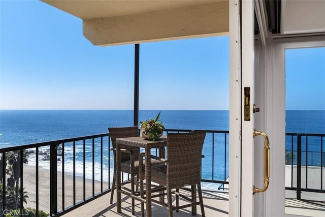 balcony with a water view and a view of the beach