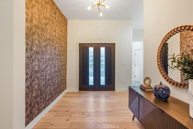 foyer featuring french doors, a chandelier, and light wood-type flooring