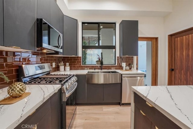 kitchen featuring stainless steel appliances, light stone counters, and tasteful backsplash