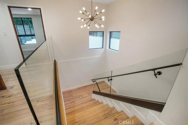 staircase with hardwood / wood-style floors and a notable chandelier