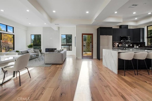 kitchen with backsplash, fridge, light hardwood / wood-style flooring, a breakfast bar, and sink