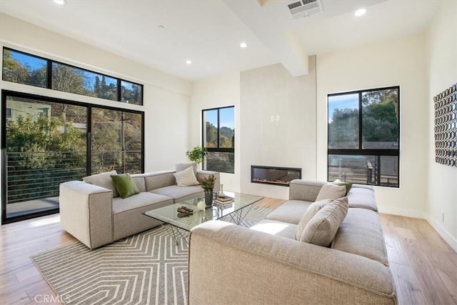 living room with beam ceiling, a wealth of natural light, and light hardwood / wood-style flooring