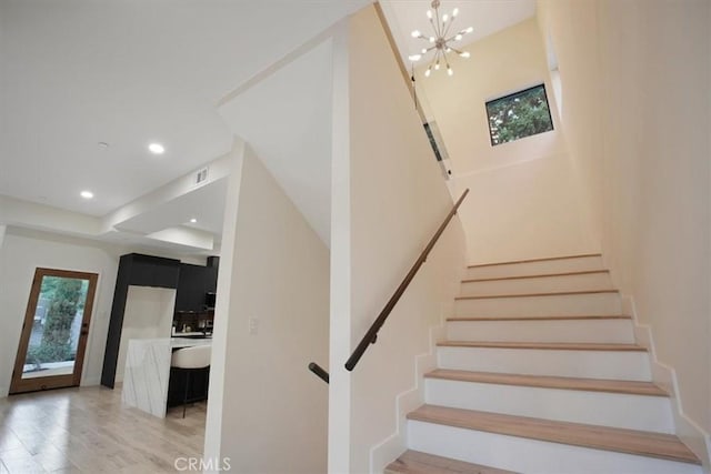 stairs featuring wood-type flooring and a chandelier