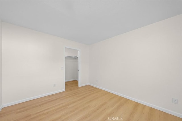 unfurnished bedroom with a spacious closet, light hardwood / wood-style flooring, and a closet