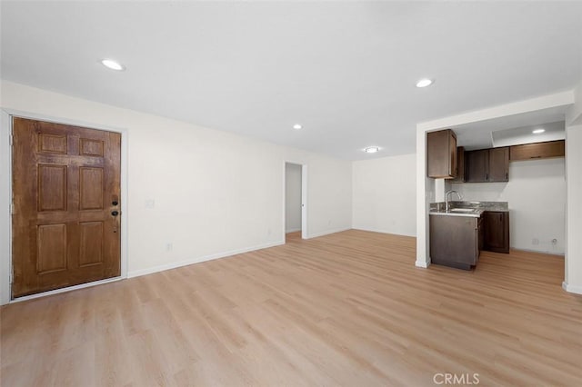 unfurnished living room with light wood-type flooring and sink