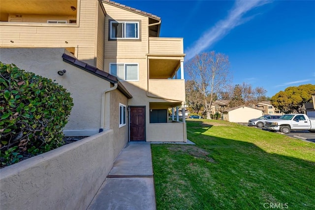 view of property exterior featuring a balcony and a yard