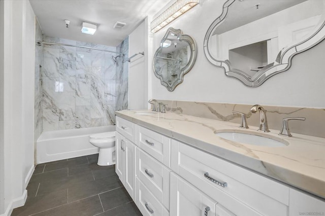 full bathroom featuring toilet, vanity, tiled shower / bath, and tile patterned flooring